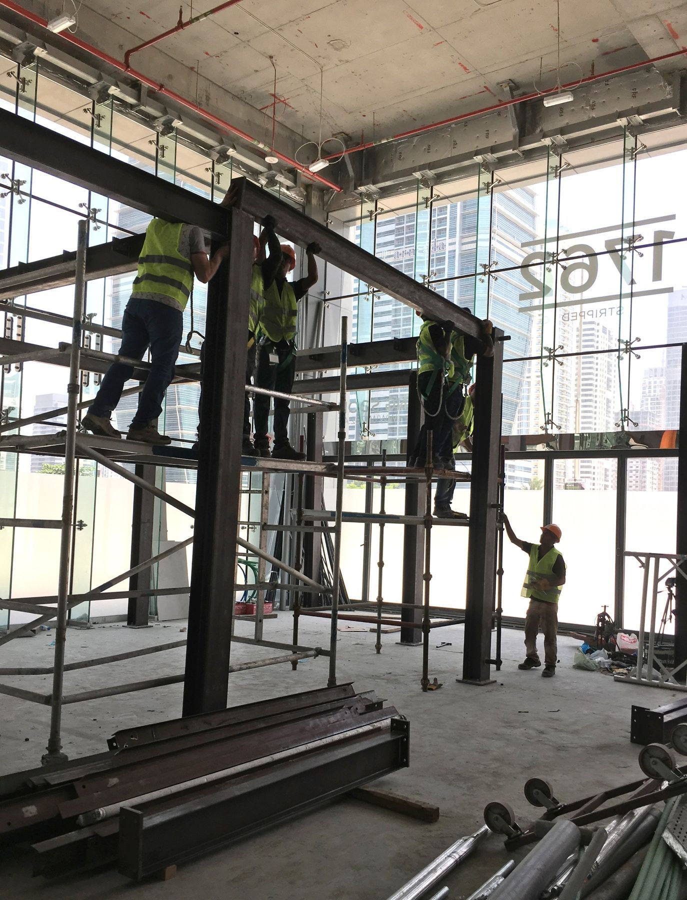 Site team erecting the steel mezzanine inside the glass shell at One JLT