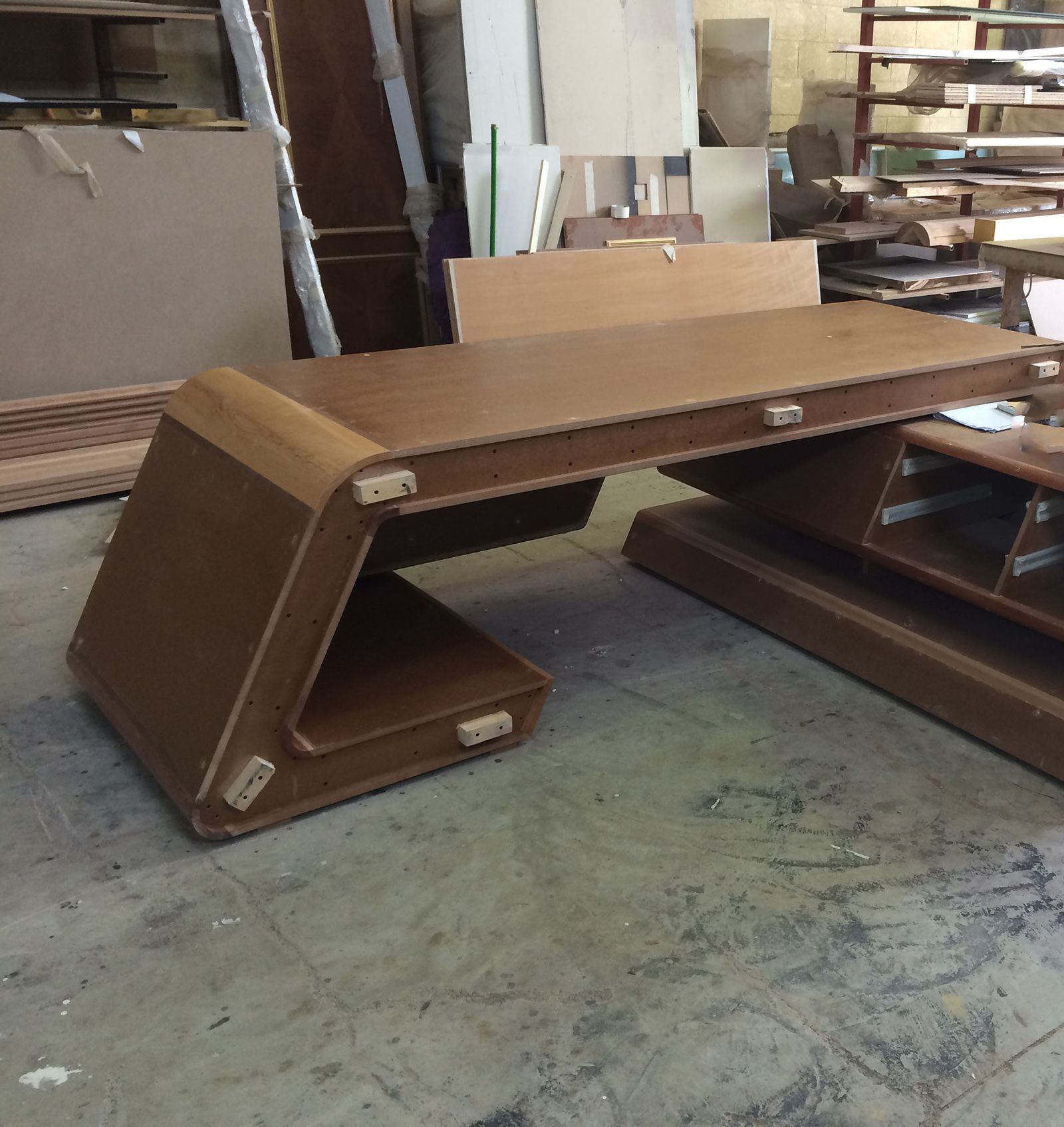 A curved timber desk being assembled